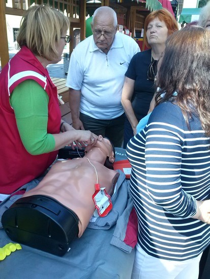 Predavateljica prve pomoči pri prikazu temeljnih postopkov oživljanja z uporabo defibrilatorja.